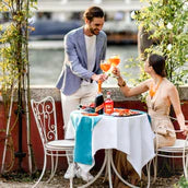 Two people enjoying a meal together at an outdoor table with a scenic background.