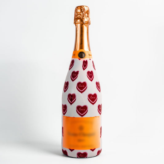 Bottle of champagne with a decorative wrap featuring red hearts on a white background