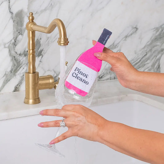 Person holding a bottle of 'Pinof Cleano' next to a sink with water flowing.